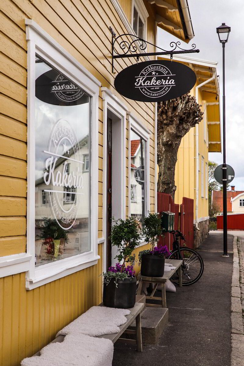 Det gula huset på Torsredsvägen med Kråkestans Kakerias hängande skylt och blomkrukor vid entrén